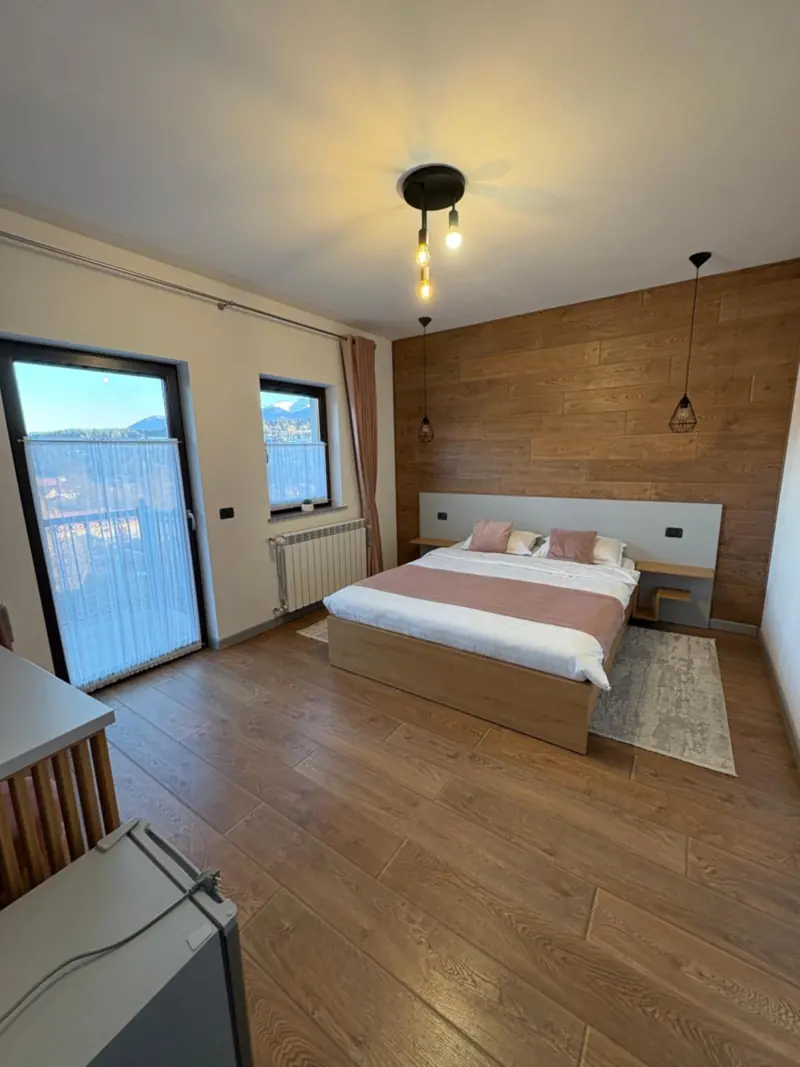 Cameră dublă cu perete îmbrăcat în lemn și ușă spre balcon